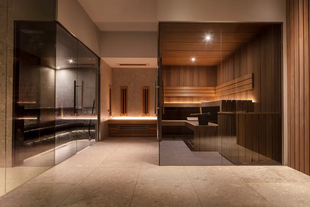 Sauna en stoomcabine achter glazen wanden, met warm licht op de banken