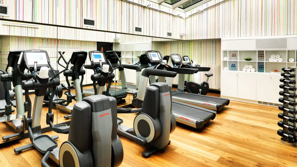 Fitnessruimte met loopbanden, crosstrainers en een rek met gewichten