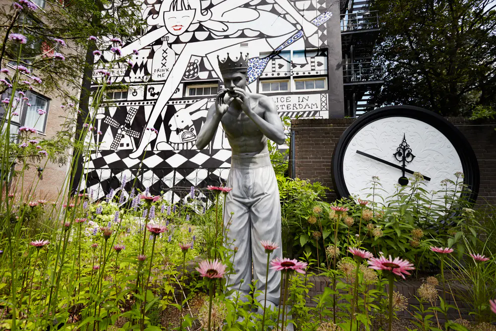 De tuin van Andaz met een beeld, planten en een zwart-wit beschilderde muur