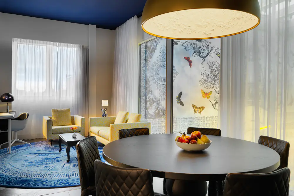 Een suite van Andaz met een ronde tafel, fauteuils en een grote lamp