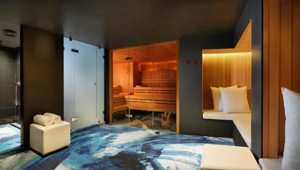 De sauna en rustplek van Essence Spa met houten wanden en een blauw tapijt