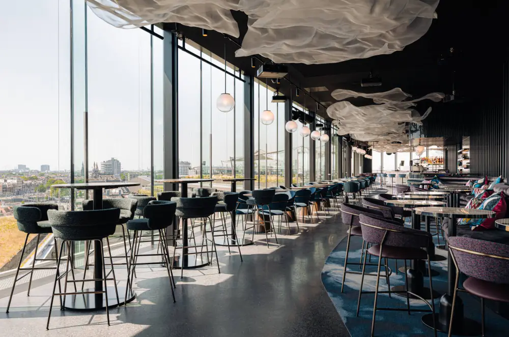 Het terras van rooftopbar LuminAir met tafels langs glazen wanden en uitzicht over de stad