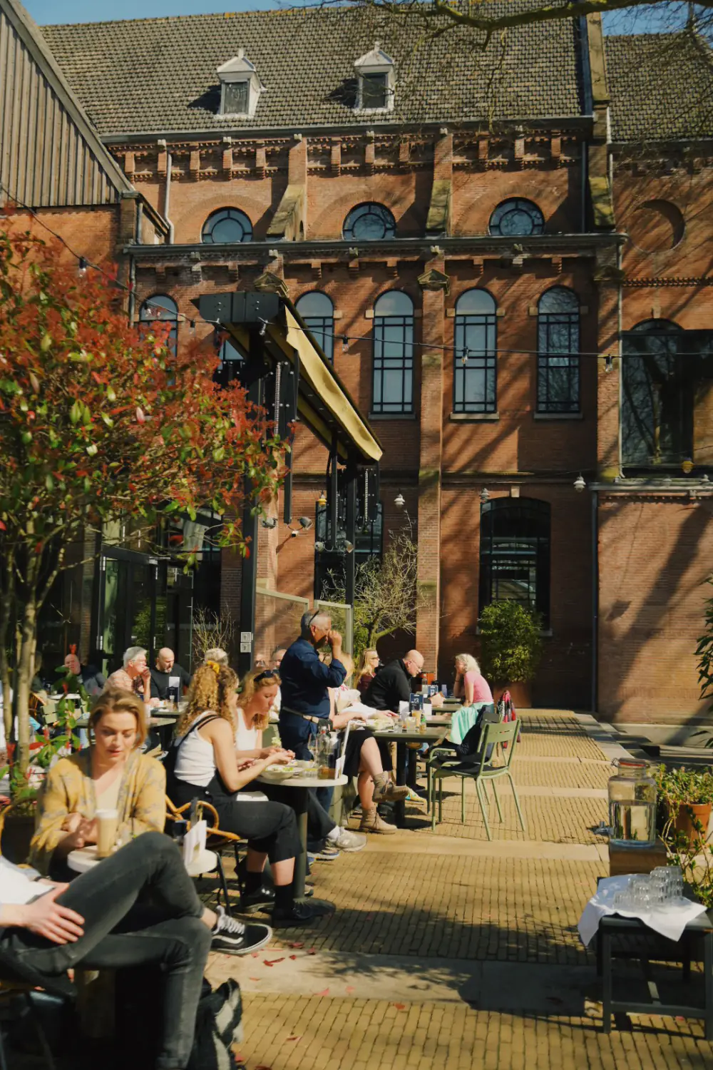 Gasten op het terras van PARK voor de gevel van Hotel Arena