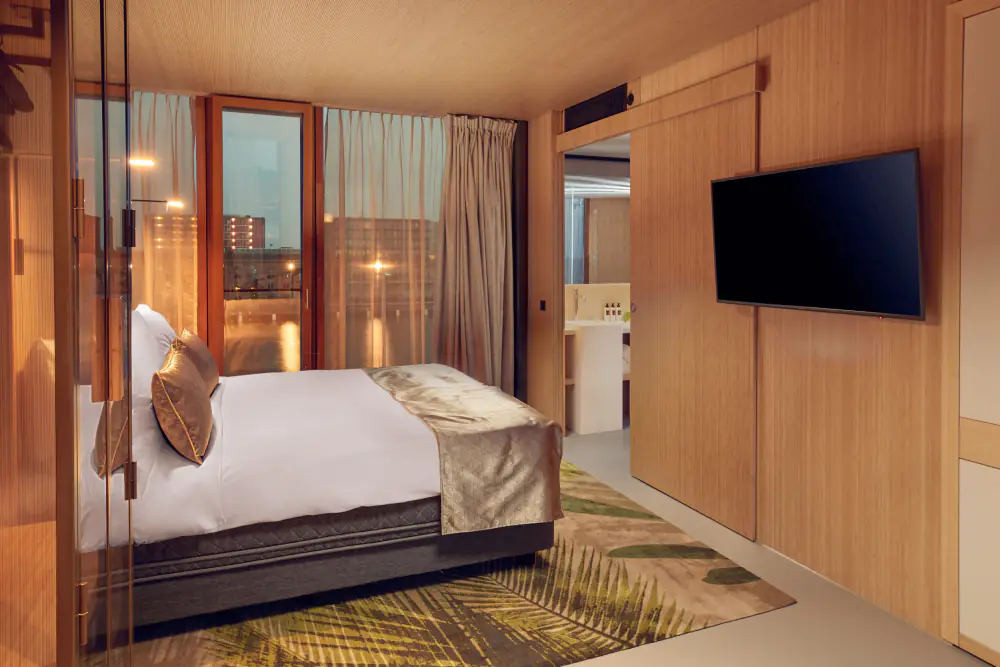 Een hotelkamer van Hotel Jakarta met een bed, houten wanden en een raam op het water