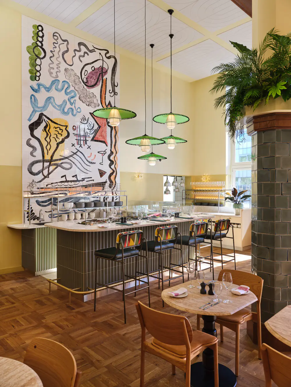 Een kunstwerk boven de bar van Breman Brasserie, met hanglampen en tafeltjes