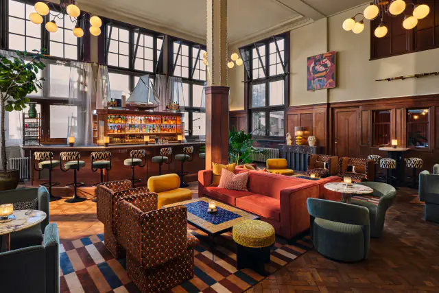 Barbue met banken in rood en groen, lage tafels, een bar en hoge ramen