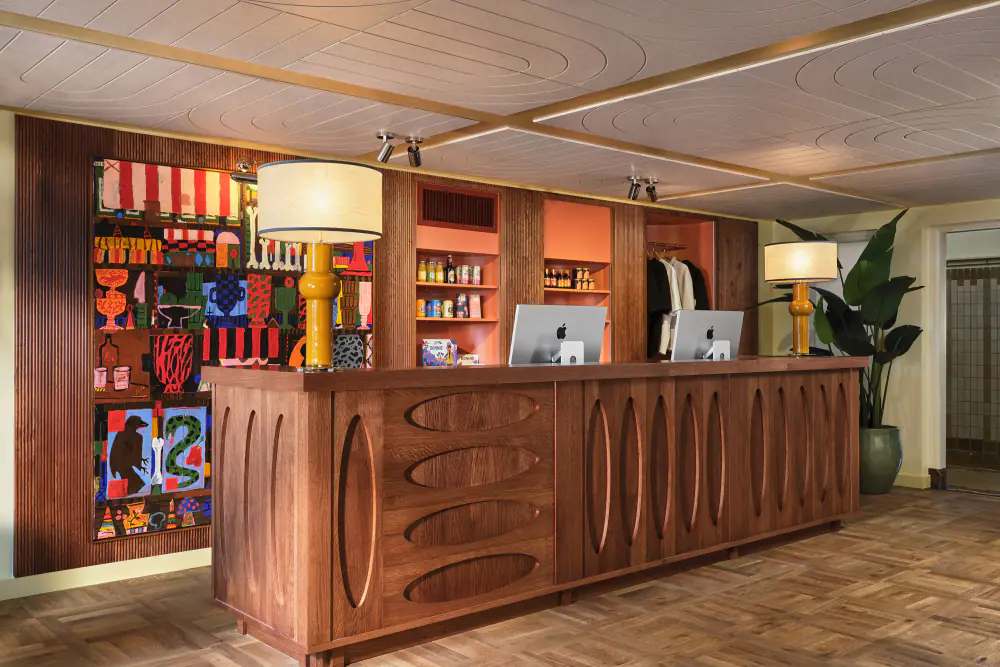 De receptie van The Hoxton met een houten balie en kasten vol boeken en spullen