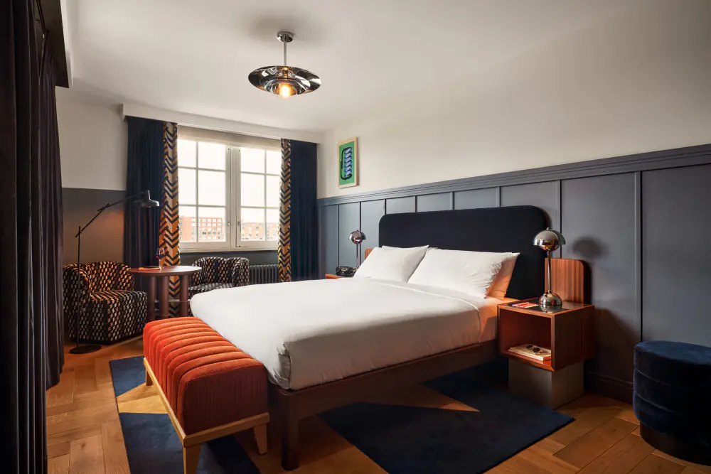 Een hotelkamer van The Hoxton met een tweepersoonsbed, blauwe wanden en een raam met kozijnen