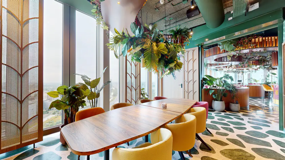Een lange houten tafel met gele stoelen in Selva, met de stad achter de ramen