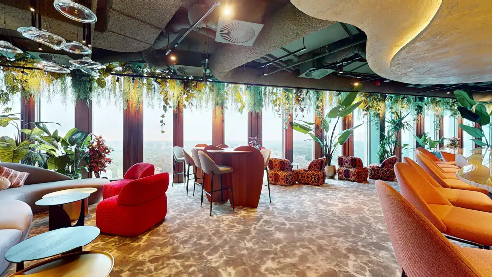 Oranje banken en rode fauteuils in Sonora Bar, met planten aan het plafond
