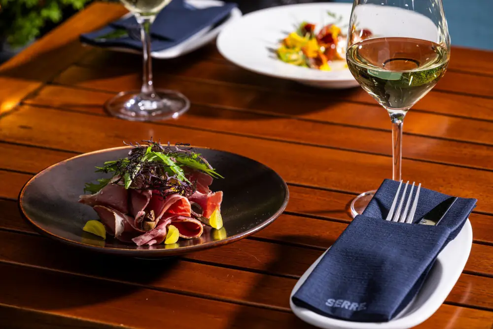 Een gerecht met een glas wijn op het terras van Serre