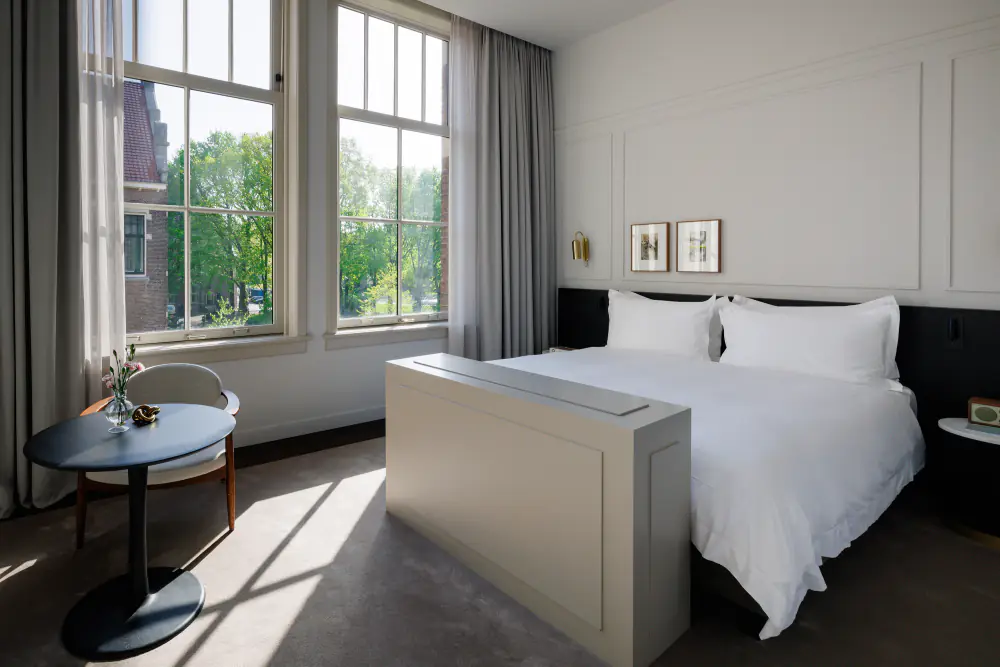 Een junior suite van Pillows met een wit bed bij hoge ramen