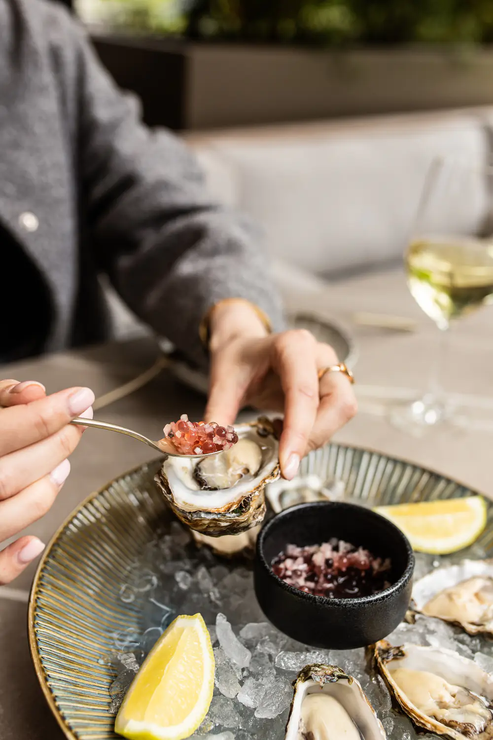Oesters met een rode dressing op ijs, aan tafel in Spring Café Brasserie, met een glas witte wijn