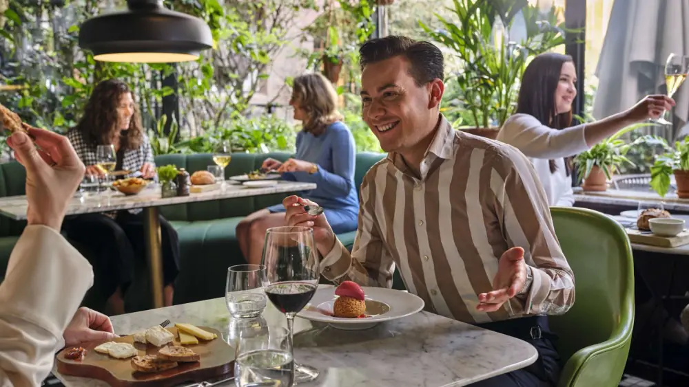 Gasten aan tafel tussen het groen van Oriole Garden Bistro