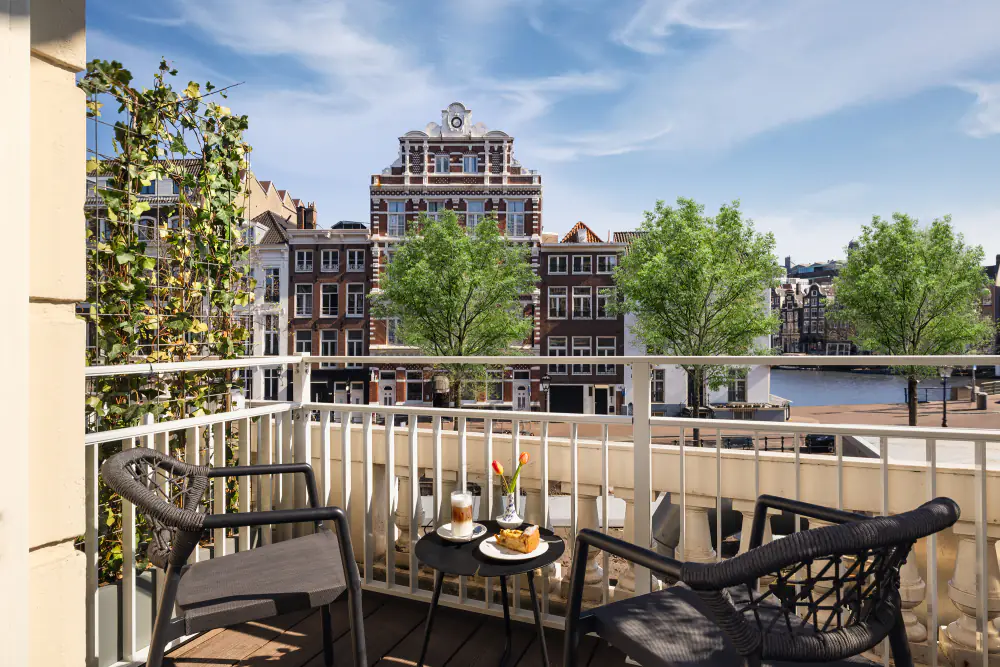 Een balkon van Tivoli Doelen met twee stoelen en uitzicht op de Amstel