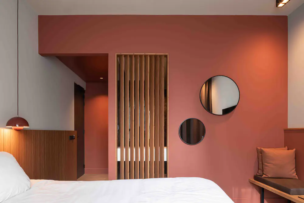 Een hotelkamer van Zuiver met een terracotta wand, een bed en een houten paneel