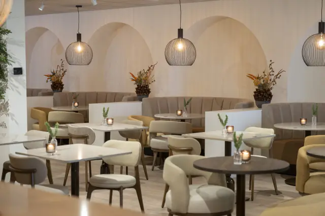 Het loungerestaurant van Zuiver met lichte stoelen, ronde tafels en bogen in de wand