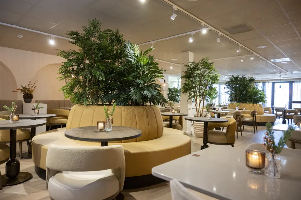 Zuiver Restaurant: een lichte zaal met ronde banken rond een grote plant
