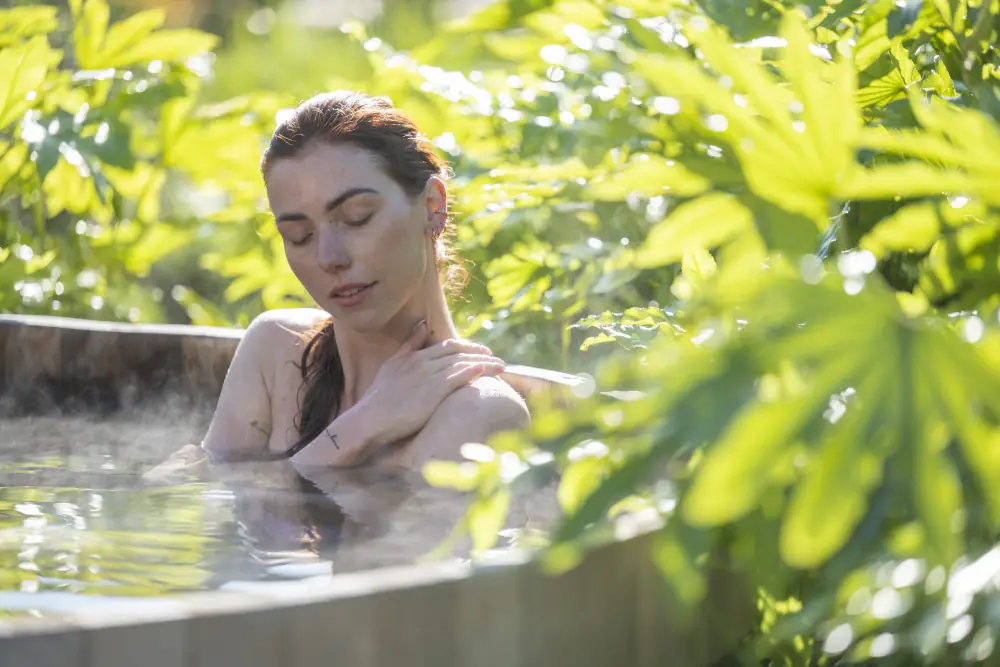 Een vrouw ontspant in een warm bad tussen het groen bij Zuiver