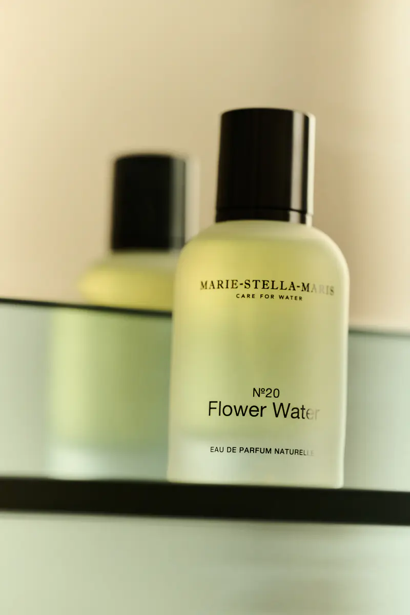 Een flacon eau de parfum op een glazen plank voor een spiegel