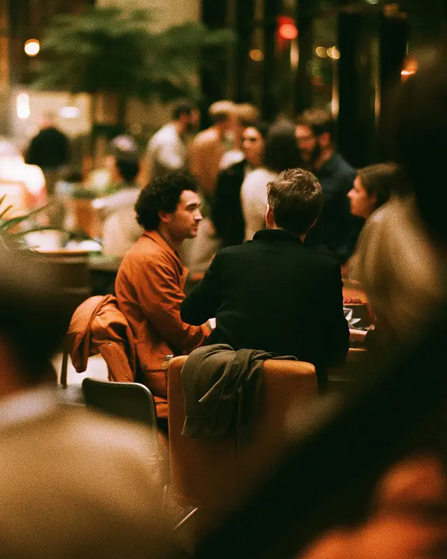 Busy restaurant in warm evening light, guests talking at the table.