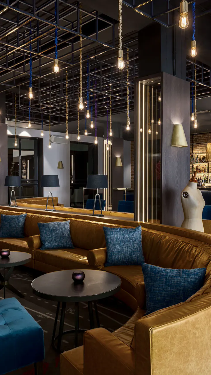 Bar The Tailor, cocktailbar in Amsterdam centrum: een lange leren bank, blauwe fluwelen fauteuils en lampen aan koorden boven de bar