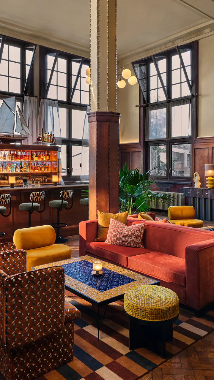 Barbue met banken in rood en groen, lage tafels, een bar en hoge ramen