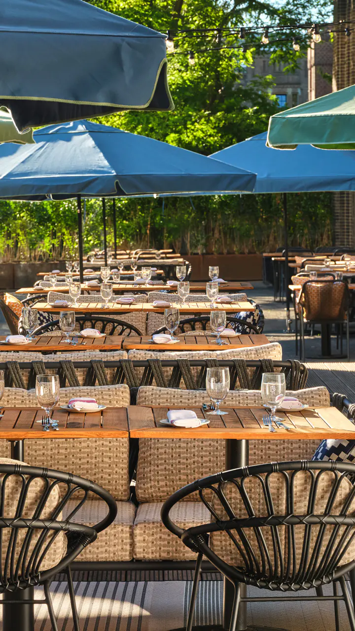 Het terras van Breman Brasserie met tafels, stoelen en blauwe en groene parasols