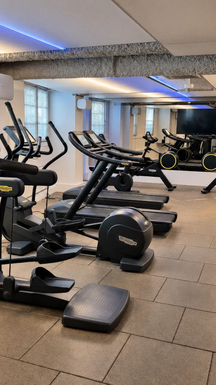 Het fitnesscentrum van Clayton Hotel Amsterdam American met crosstrainers en loopbanden van Technogym bij de ramen, en een spiegelwand