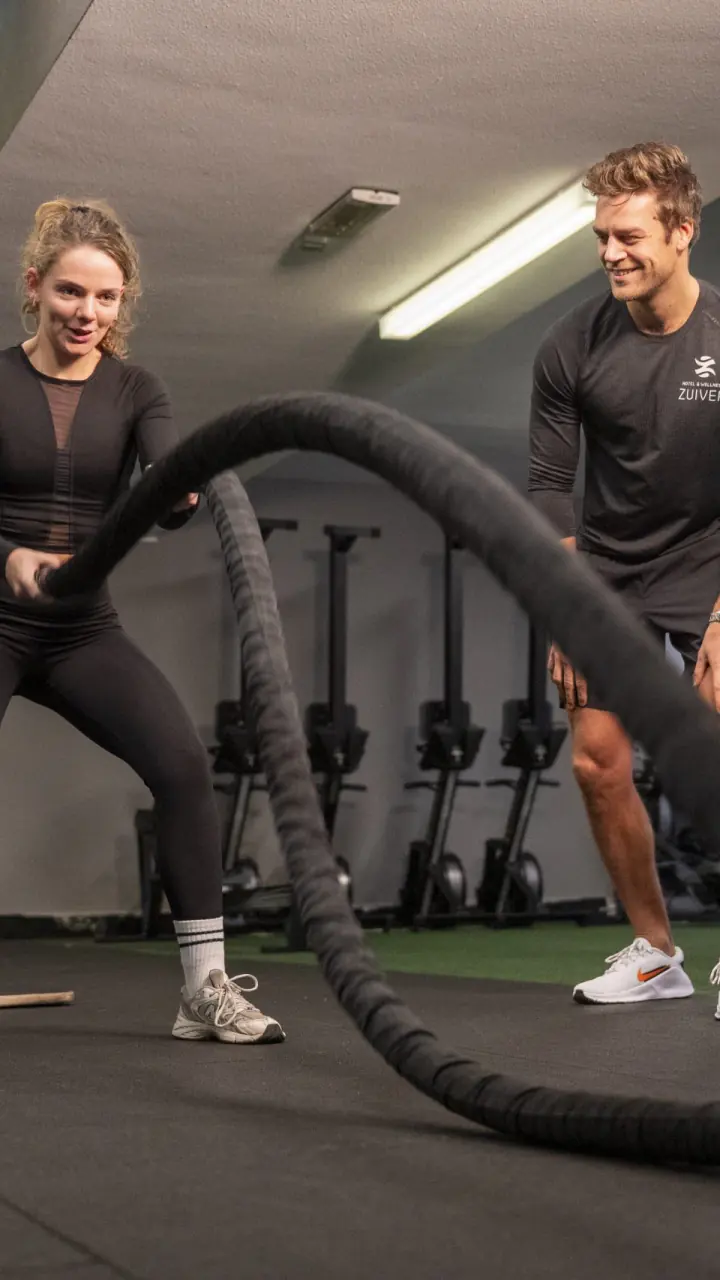 Twee mensen trainen met battle ropes in de sportzaal van Fitness Zuiver