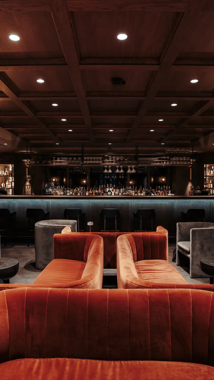 Fitz’s Bar met donkere wanden, een ronde oranje bank en lage tafels