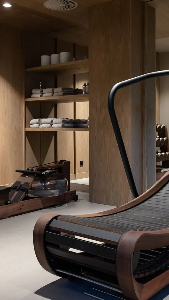 De gym van Pillows met een loopband en toestellen tegen een houten wand