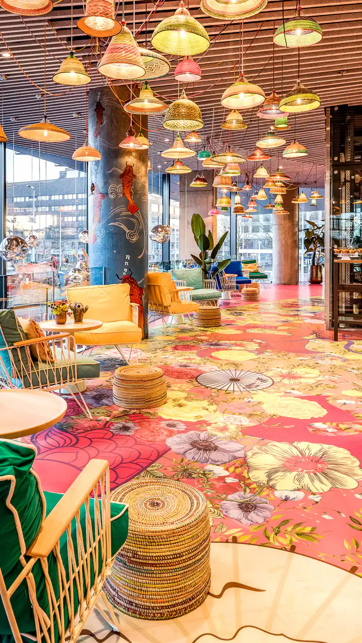 Moana Bar met gekleurde gevlochten lampen aan het plafond, een tapijt met bloemen en zitjes bij de ramen