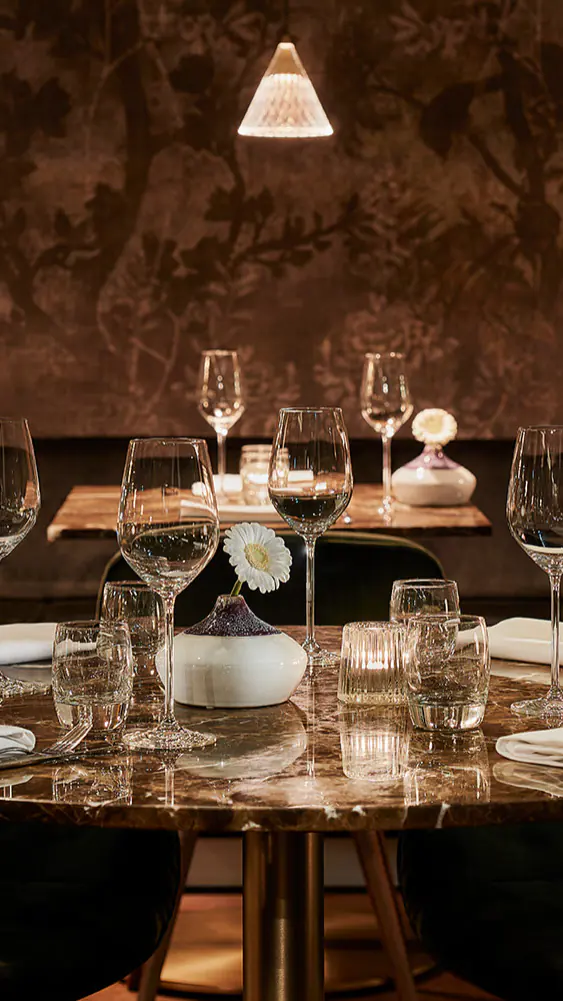 Restaurant Omber met ronde tafels, groene stoelen en schilderingen aan de wand