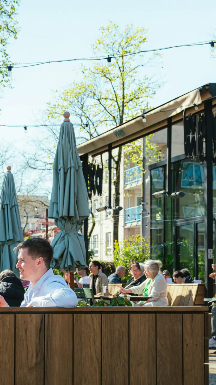 Het terras van PARK in het Oosterpark, met gasten aan tafels onder de bomen