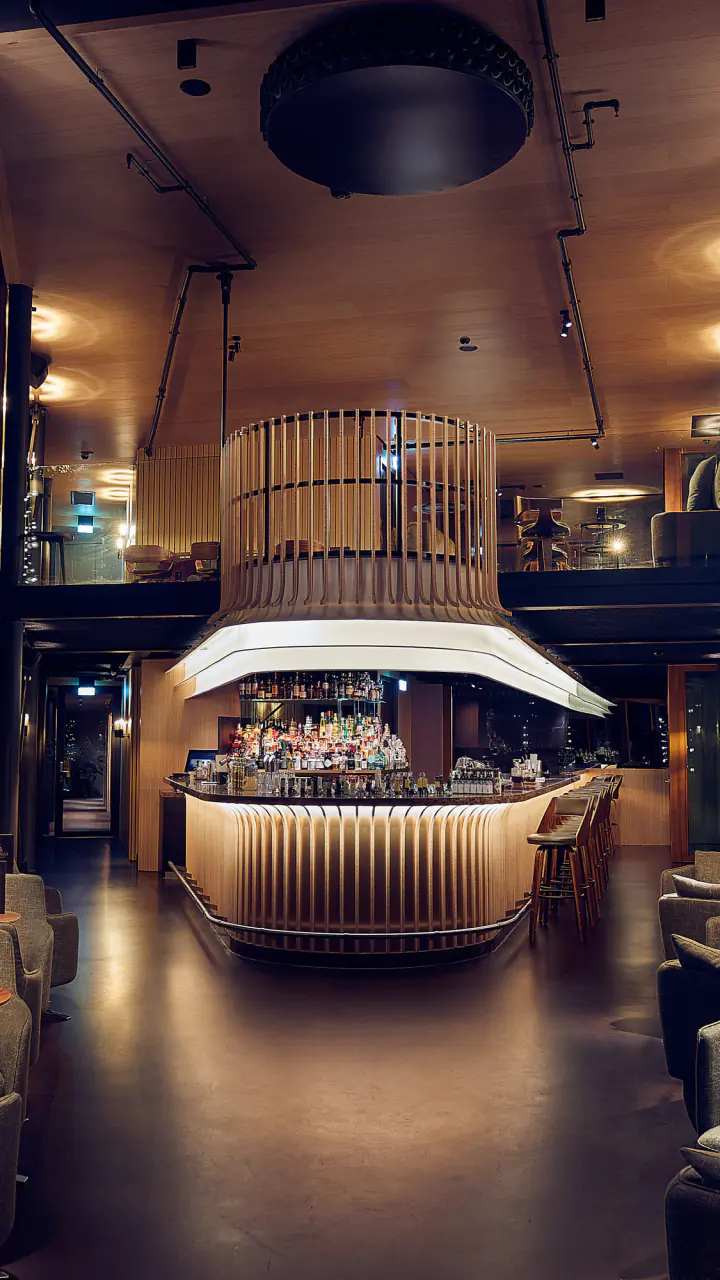 Skybar Malabar met een ronde bar in een hoge, donkere ruimte met houten lamellen