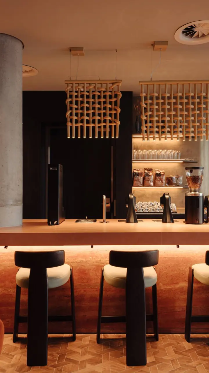 De bar van WE ARE EDN met hoge krukken en een verlichte bar met houten panelen