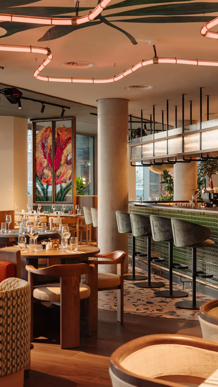 Restaurant WE ARE EDN met tafels, banken en grote kleurige wandschilderingen